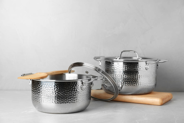 New clean saucepans on table against grey background, space for text - Foto, Bild