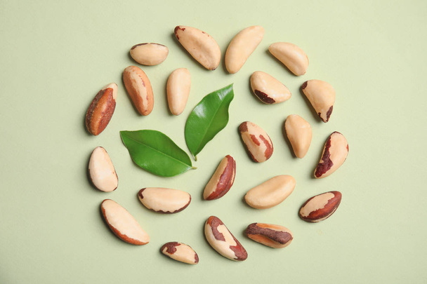Flat lay composition with Brazil nuts and leaves on color background - Fotografie, Obrázek