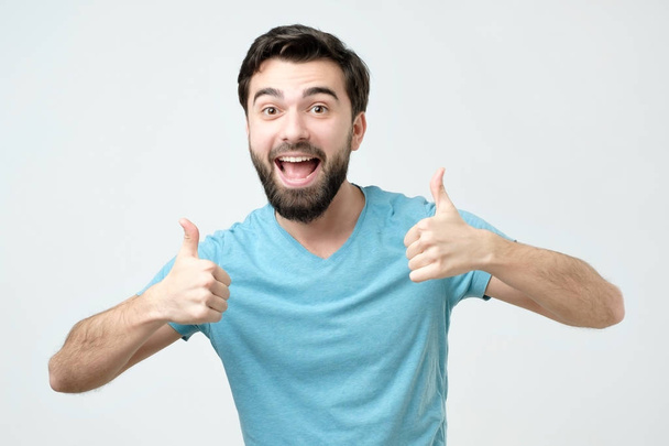 Smiling man showing both thumbs up and looking at camera. Handsome guy advertising something - Photo, Image