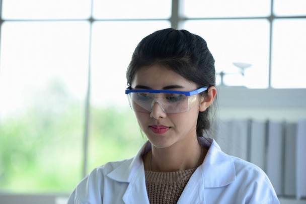 Jonge wetenschappers experimenteren met wetenschap op Aziatische wetenschapper een reageerbuis houden in een laboratorium. Wetenschappers werken in science labs.  - Foto, afbeelding