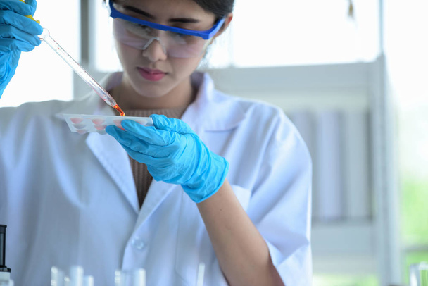 Jóvenes científicos están experimentando con la ciencia en el científico asiático sosteniendo un tubo de ensayo en un laboratorio. Los científicos están trabajando en laboratorios de ciencias
.  - Foto, Imagen