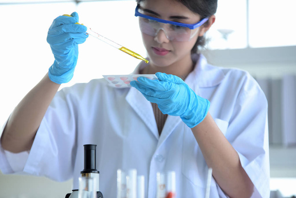 junge Wissenschaftler experimentieren mit Wissenschaft an einem asiatischen Wissenschaftler, der in einem Labor ein Reagenzglas hält. Wissenschaftler arbeiten in wissenschaftlichen Laboren.  - Foto, Bild