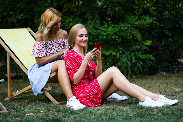 kahdella ystävällä on hauskaa puistossa, he käyttävät älypuhelinta
 - Valokuva, kuva
