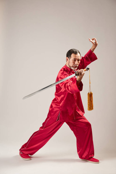 Maestro mayor practicando qi qong taijiquan en el estudio. Ejercicio de respiración y movimientos de arte marcial, gimnasia tradicional china de gestión de la energía qi
 - Foto, Imagen