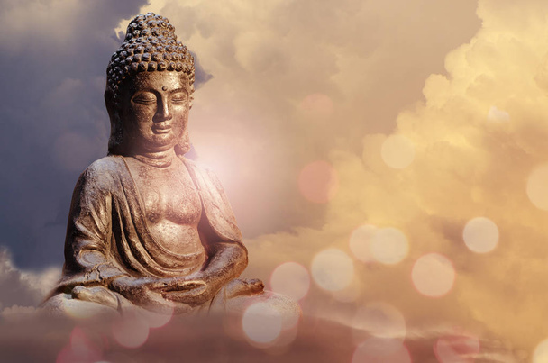 Buddha patsas istuu meditaatio poseeraa auringonlaskua vastaan taivas kultainen sävyjä pilvet
. - Valokuva, kuva