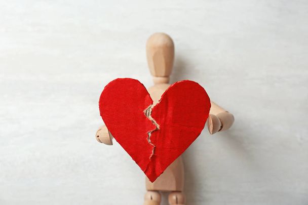 Wooden puppet with torn cardboard heart on gray background. Relationship problems - Foto, Imagem