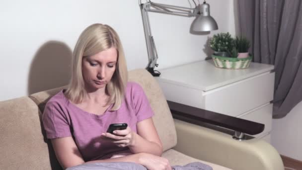 Young blond woman answering friend message in social network application, searching for information - Imágenes, Vídeo