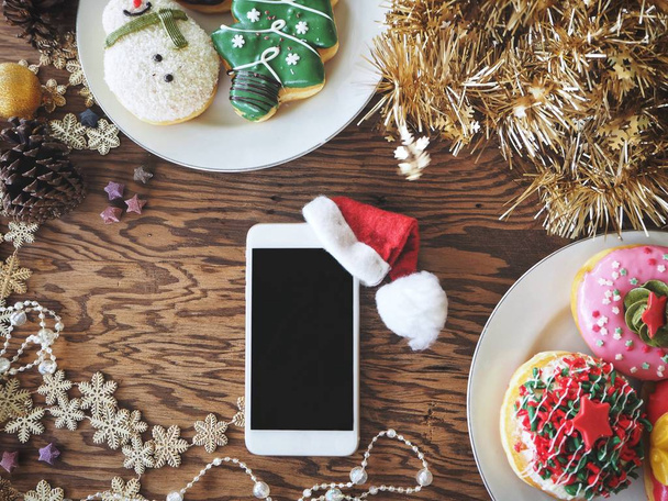 Smart phone with christmas hat and donuts - Φωτογραφία, εικόνα