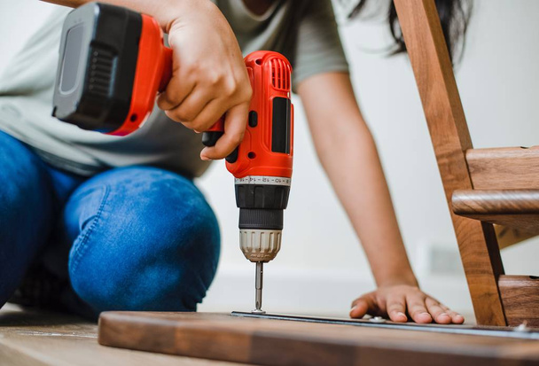 Attractive and confident constructor carpenter or builder man working wood with electric drill at industrial construction site. In installation and renovation - Photo, image