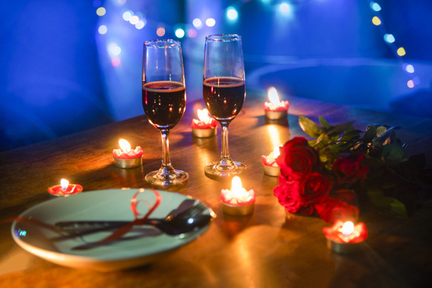 ロマンチックなバレンタイン ディナー コンセプトが大好き/フォーク スプーン プレートとカップルのシャンパン グラス バラの木製テーブル ディナー夜の明るい背景でろうそくの明かりで飾られたロマンチックなテーブルセッティング  - 写真・画像