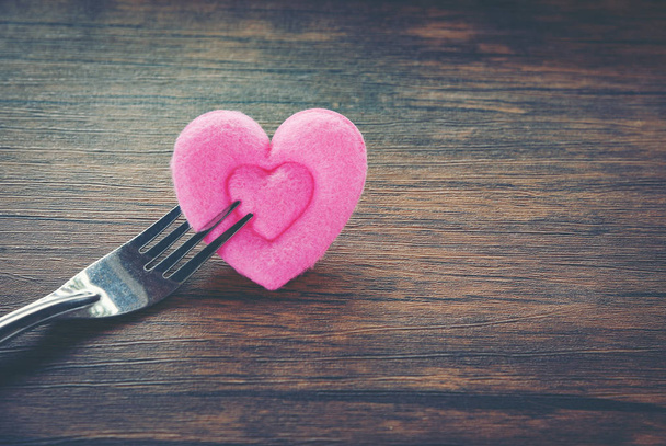 Valentines dinner romantic love food and love cooking concept - Romantic table setting decorated with fork and pink heart on wooden rustic texture background  - Photo, Image
