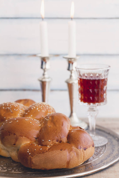 Szombati vagy szombat kiddush szertartás kompozíció egy hagyományos édes friss vekni Barhesz kenyér, pohár vörös kóser bor és gyertyák, a szüreti fa háttér  - Fotó, kép