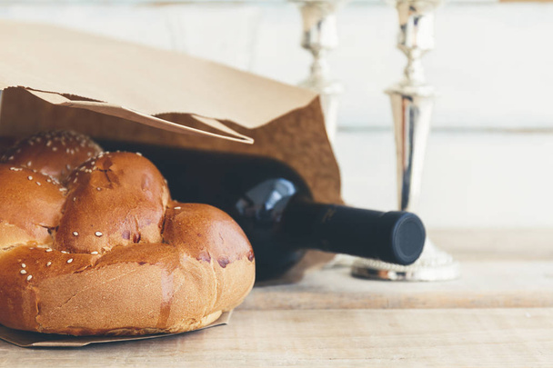 Szombati vagy szombat bevásárlás kompozíció egy hagyományos édes friss vekni kenyeret Barhesz egy üveg vörös kóser bort egy szüreti fa háttér - Fotó, kép