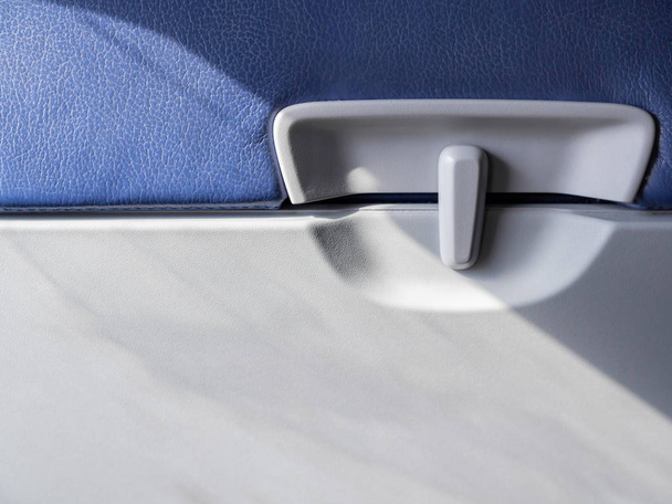 Fermez le verrou du plateau alimentaire en plastique à l'arrière des sièges en cuir bleu sur avion commercial à faible coût avec espace de copie
. - Photo, image