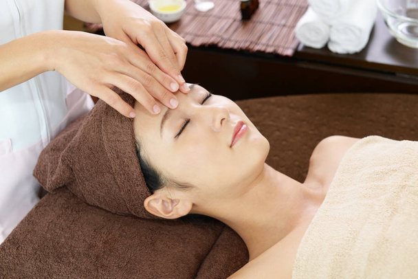 Hermosa joven recibiendo masaje facial con los ojos cerrados en un salón de spa
  - Foto, imagen