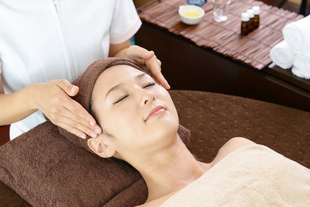 Mulher bonita recebendo massagem facial com olhos fechados em um salão de spa
  - Foto, Imagem