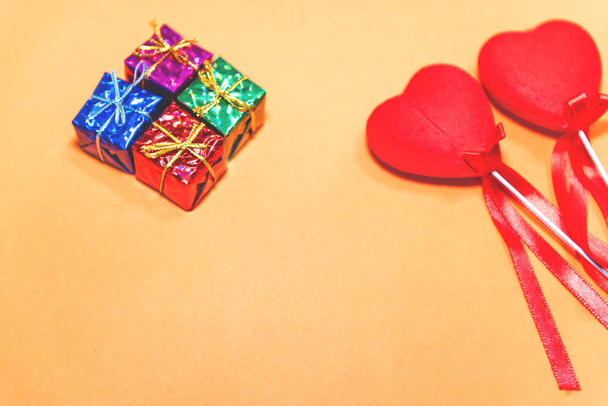 Top view of couple decorative red hearts shapes and small gift boxes on orange background.Holiday concept with isolated background. - Photo, Image