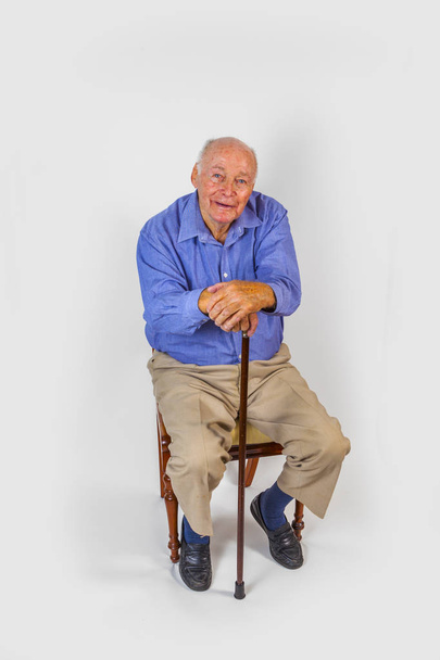 ευτυχής ηλικιωμένος άνδρας κάθεται μπροστά από ένα λευκό φόντο - Φωτογραφία, εικόνα