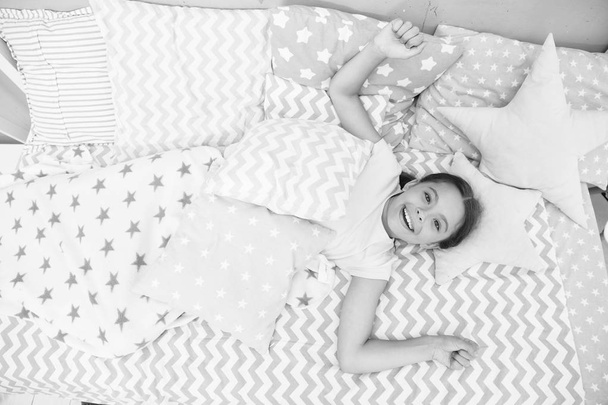 Wish her good morning. Girl child lay on bed her bedroom. Kid awake and full of energy. Pleasant time relax cozy bedroom. Girl kid relaxing in morning. Cheerful and wakeful concept - Foto, imagen