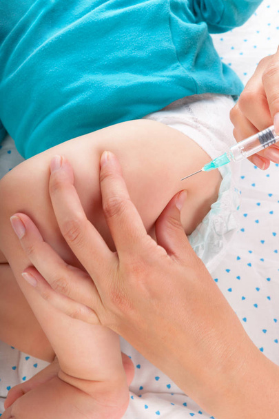 Pediatrician giving a baby boy intramuscular injection. Medicine concept. - Фото, изображение