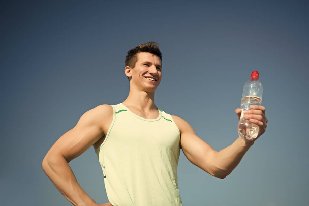 Happy man with water bottle in muscular hands - Foto, Imagen