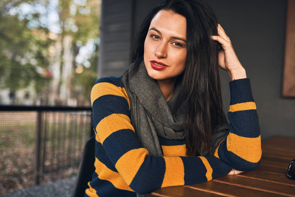 Beautiful hipster girl wears sweater sitting outdoors at cafeteria while waiting friends. Happy young woman sitting outdoors in the coffee shop wainting her coffee cup. People and lifestyle concept  - Φωτογραφία, εικόνα