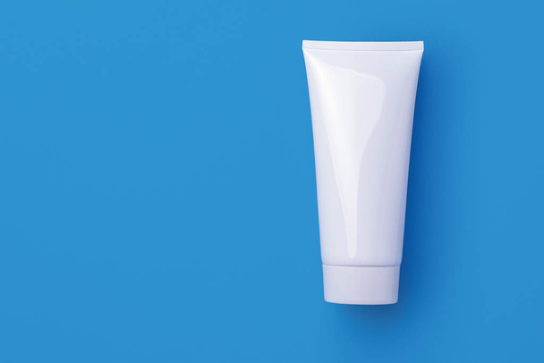 Lege witte cosmetische buis geïsoleerd op blauwe achtergrond - Foto, afbeelding