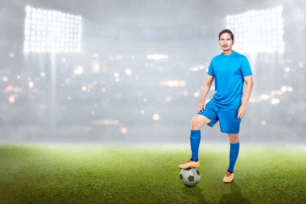 Profesional asiático fútbol jugador hombre de pie con pelota en su pierna en el estadio campo
 - Foto, imagen