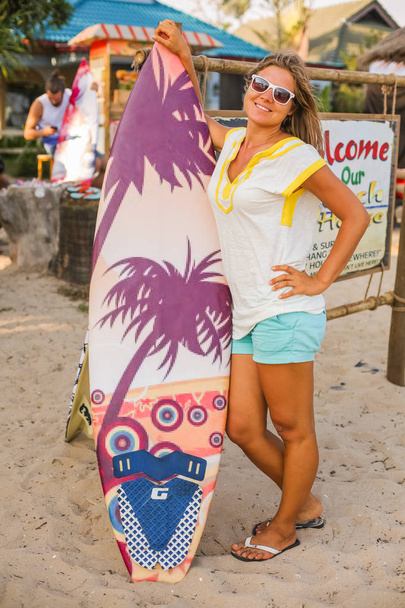 Young woman with a surf board on the sandy beach. - Photo, Image