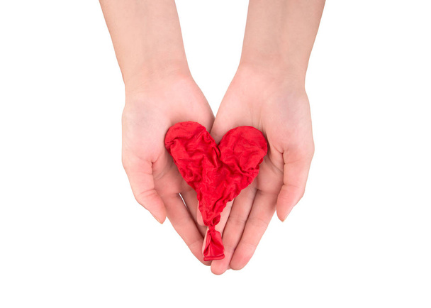 Withered red heart as a symbol of dead love. A dry red heart in the palms of a girl. - Photo, Image