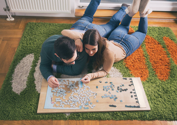 Vue du dessus du jeune couple posé sur le sol et faisant puzzle
 - Photo, image