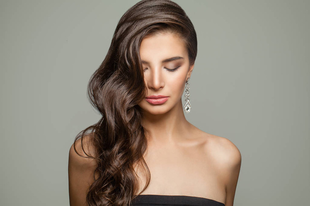 Fashion portrait of brunette woman with long curly hair, makeup and diamond jewelry earrings - 写真・画像