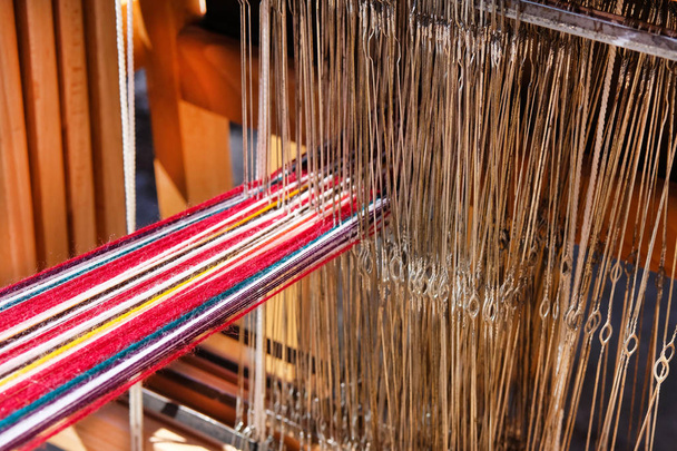 Strand de lana multicolor se enhebran en telar tradicional. Concepto nacional de tejido artesanal
. - Foto, imagen