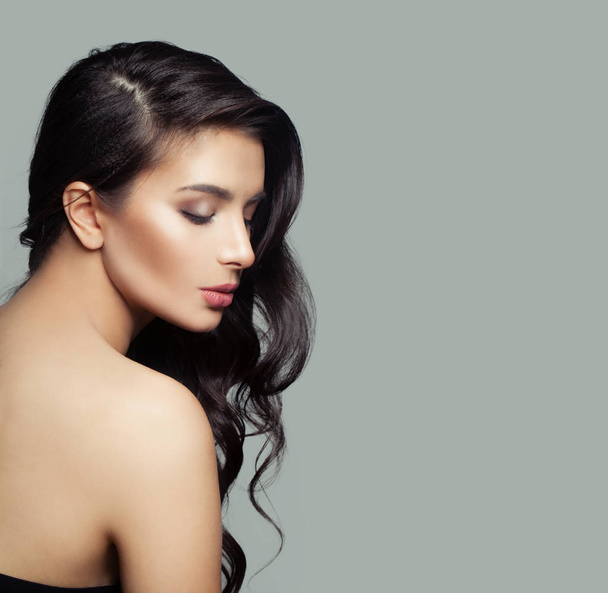 Beautiful female profile. Cute brunette woman with natural makeup and long black hair on gray background - Photo, image