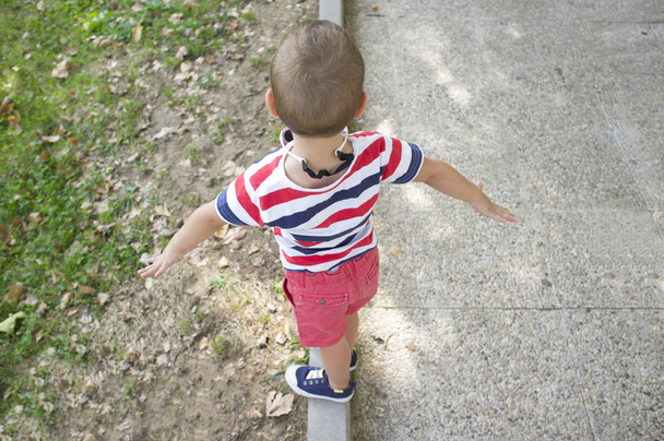 Pikkupoika esiintyy nuorallatanssijana puutarhan reunakiveyksellä. Koulutus tasapaino lapsille käsite
  - Valokuva, kuva