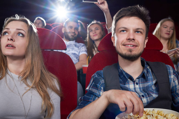 Вид спереди, когда пара ест попкорн в кино
 . - Фото, изображение