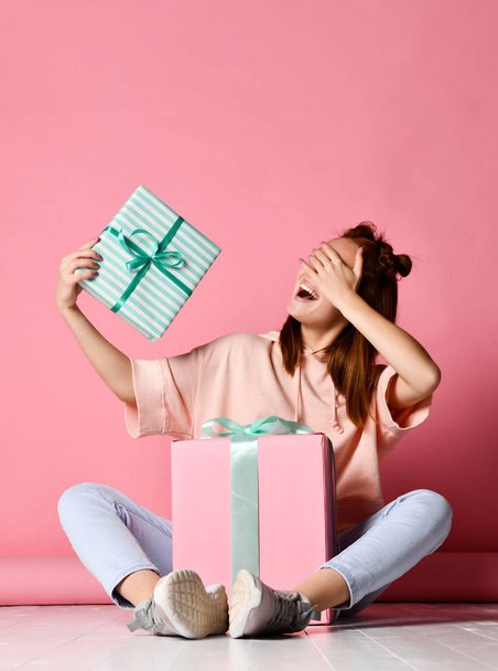 Happy young woman with gifts over pink background. - Фото, изображение