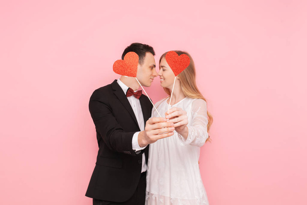 Loving couple, man and woman, holding red paper hearts, hugging on pink background, lovers day - Fotoğraf, Görsel