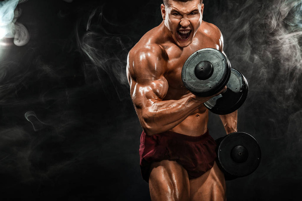 Brutal strong muscular bodybuilder athletic man pumping up muscles with dumbbell on black background. Workout bodybuilding concept. Copy space for sport nutrition ads. - Photo, Image