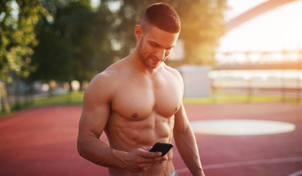 Fitness training outdoors. Handsome man working exercises in early morning with sunrise. Muscular man training outside. Sunny fitness morning. - Photo, image