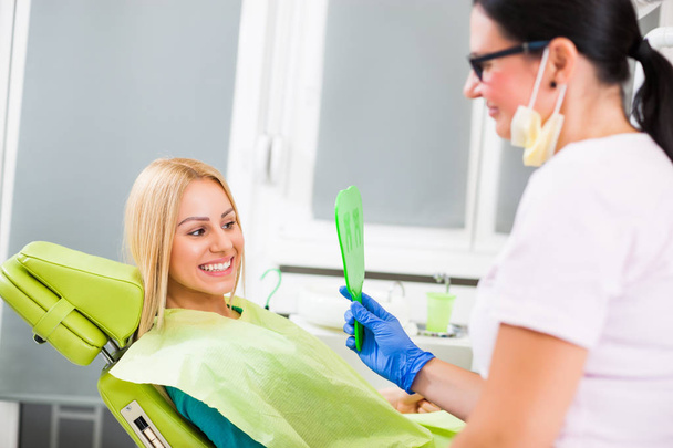 Giovane donna guardando i denti dopo un trattamento dentale di successo.  - Foto, immagini