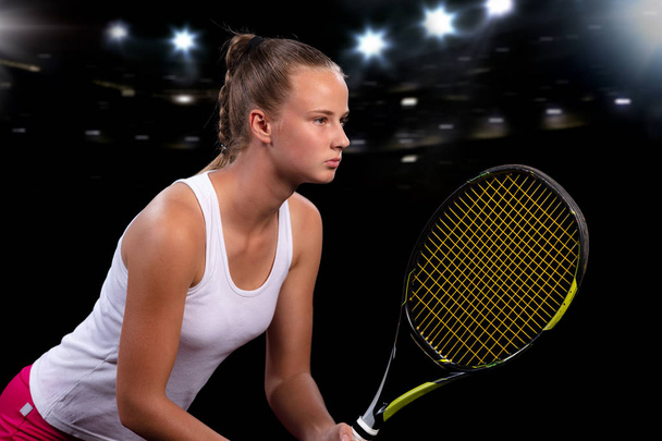 Beautiful girl tennis player with a racket on dark background with lights - Foto, afbeelding