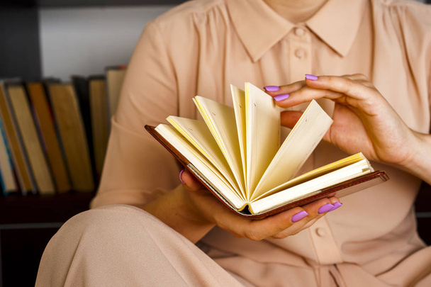 Hafif elbiseli genç kız bir kitap okuyor. Kadın elleri ellerinde bir kitap tutuyor. - Fotoğraf, Görsel