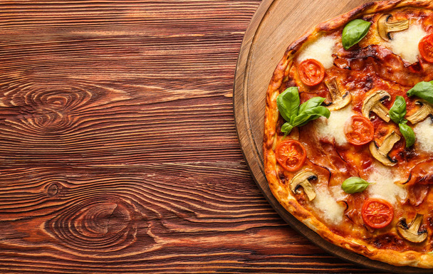 Deliciosa pizza sobre fondo de madera, vista superior
 - Foto, Imagen