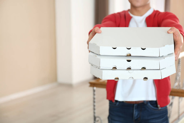 Jovem segurando caixas de pizza dentro de casa
 - Foto, Imagem