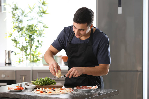 Nuori mies valmistelee maukasta pizzaa pöydässä
 - Valokuva, kuva