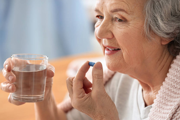 Elderly woman taking pill at home - Foto, afbeelding