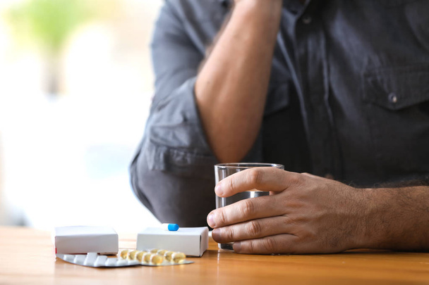 Homme mûr avec différentes pilules et verre d'eau à table
 - Photo, image
