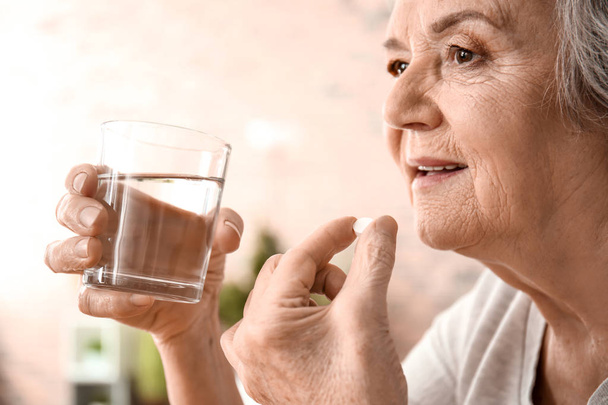 Mulher idosa tomando pílula em casa
 - Foto, Imagem