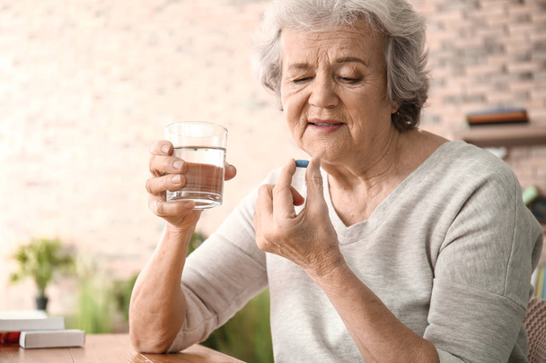 Elderly woman taking pill at home - Fotoğraf, Görsel